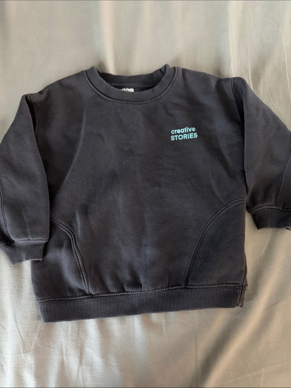 Zara black sweatshirt with teal "creative STORIES" text